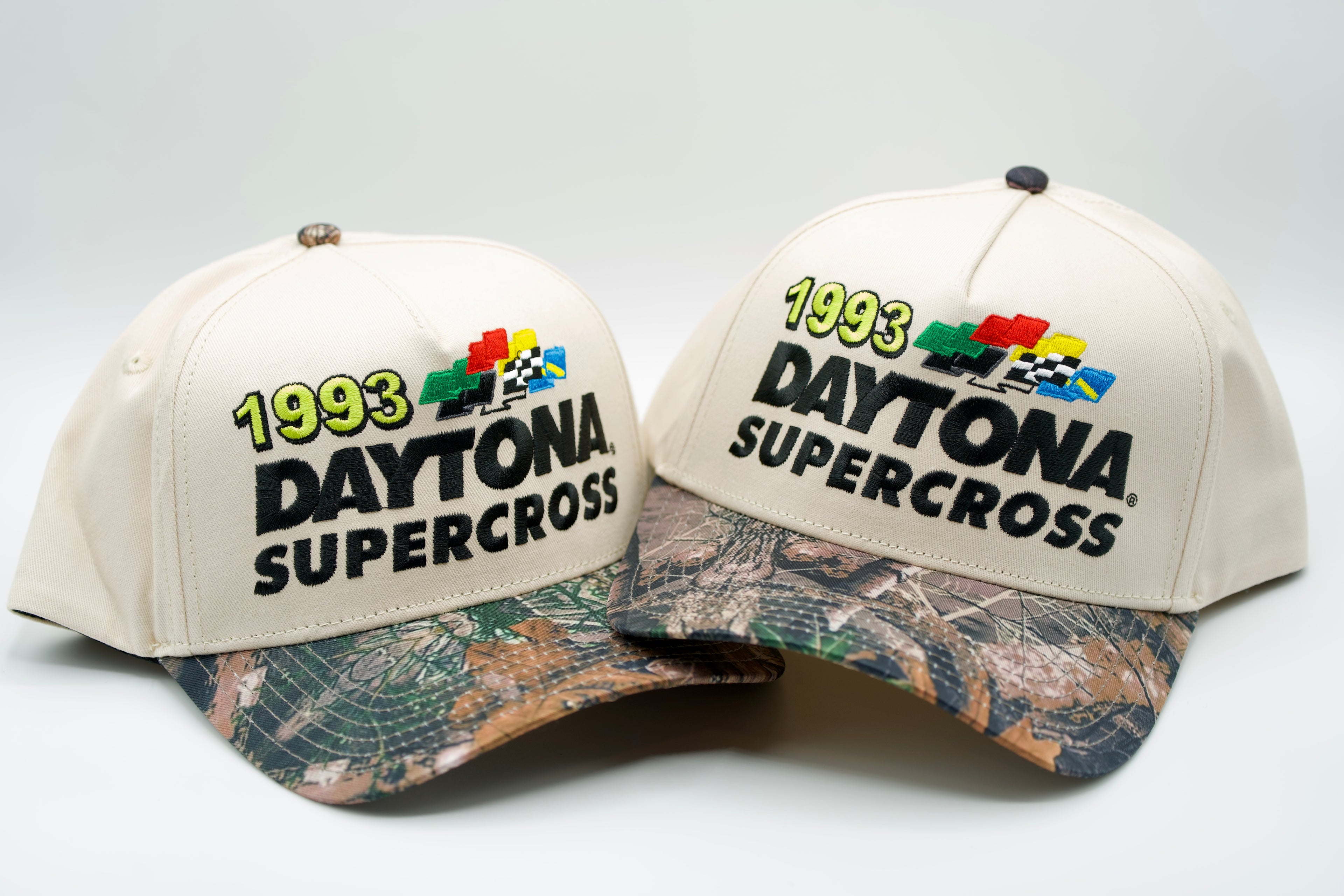 Two Daytona Supercross hats with camouflage brims on a white background